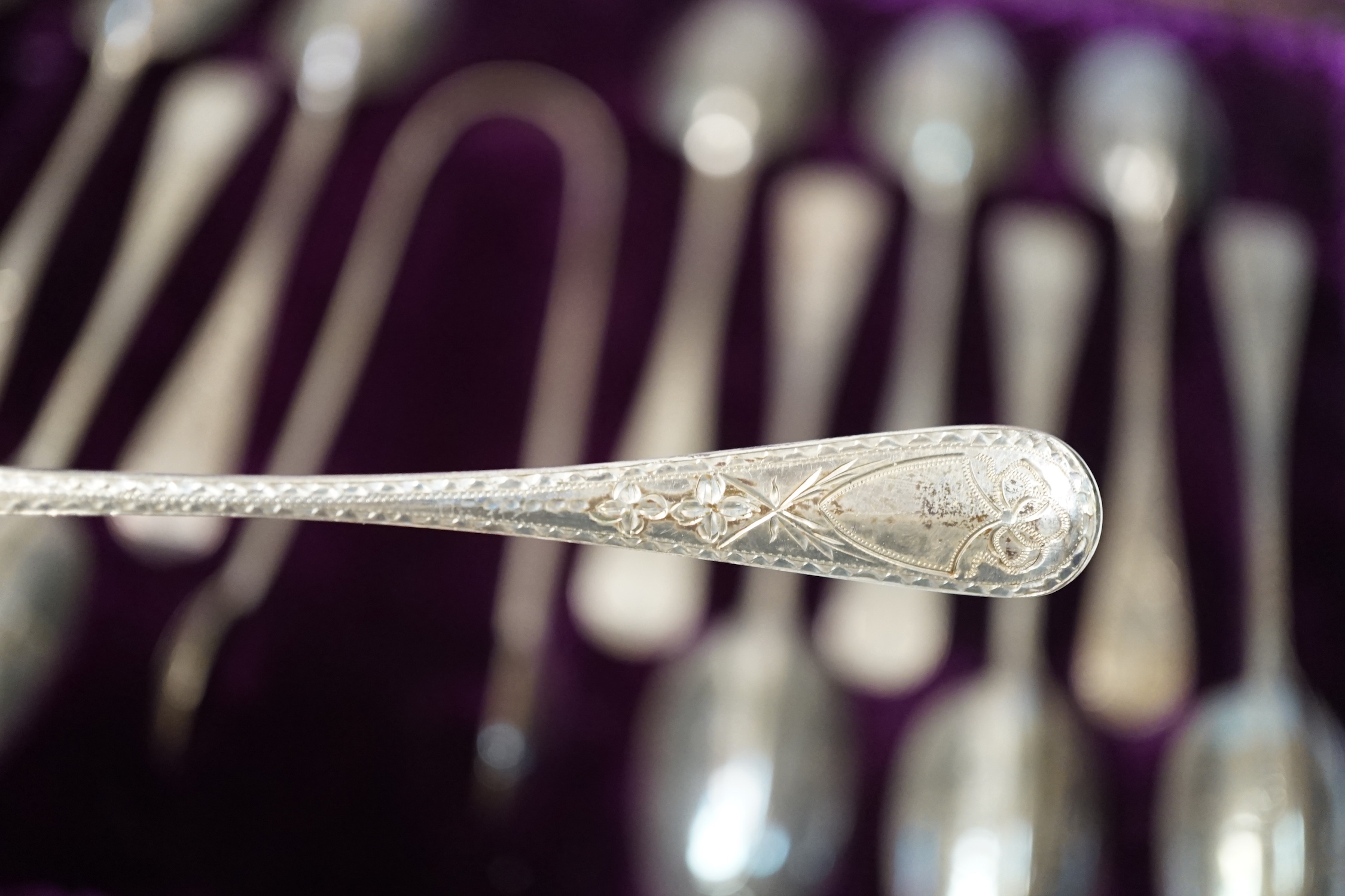 A cased set of twelve Victorian engraved silver rat tail pattern teaspoons with sugar tongs, George Adams, London, 1882.